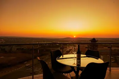 a table and chairs with a sunset in the background at Aburi at Ellipse Waterfall in Midrand