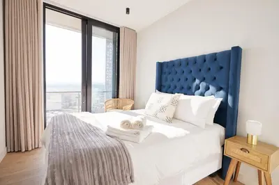 a bedroom with a large bed with a large window at Aburi at Ellipse Waterfall in Midrand