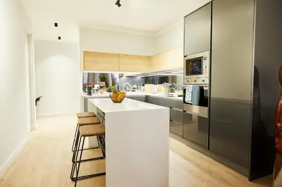 a kitchen with a white counter and stools at Aburi at Ellipse Waterfall in Midrand