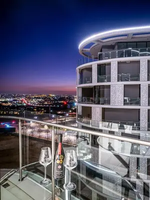 a bottle of wine on the balcony of a building at eKhaya at Ellipse Waterfall City in Midrand