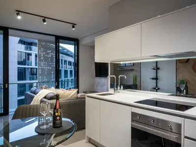 a kitchen with a couch and a table with a bottle of wine at eKhaya at Ellipse Waterfall City in Midrand