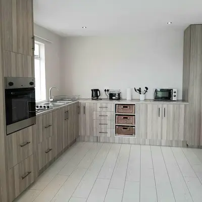 a kitchen with wooden cabinets and a white tile floor at Manz' amahle Guest Cottage in Hartbeespoort