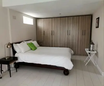 a bedroom with a large white bed and wooden cabinets at Manz' amahle Guest Cottage in Hartbeespoort