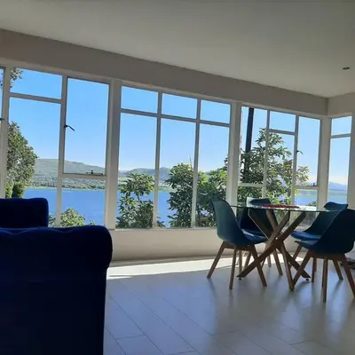 a living room with a table and chairs and windows at Manz' amahle Guest Cottage in Hartbeespoort