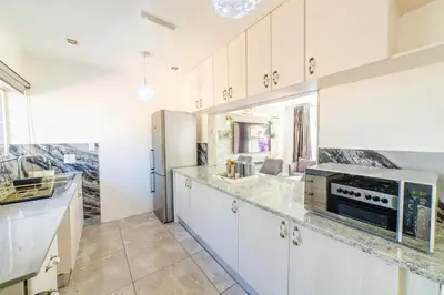 a kitchen with white cabinets and a sink and a microwave at Homes of Ace 3 bedroom Villa in Pretoria