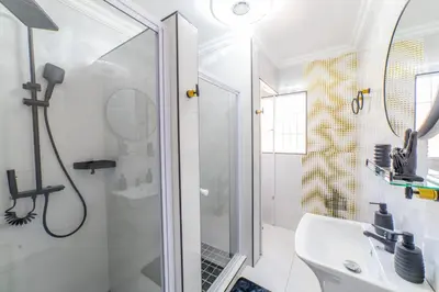 a white bathroom with a shower and a sink at Homes of Ace 3 bedroom Villa in Pretoria