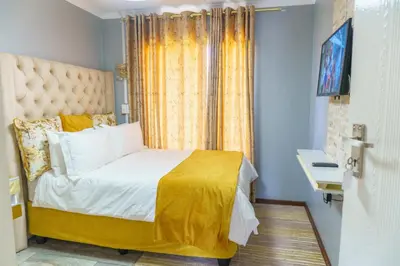 a bedroom with a large bed with a yellow blanket at Homes of Ace 3 bedroom Villa in Pretoria