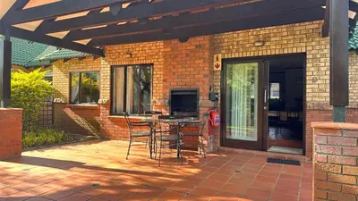 a patio with chairs and a table in front of a building at White River Selfcatering at Greenway woods House no 9 in White River