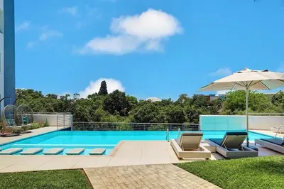 a swimming pool with two chairs and an umbrella at Luxury 2BR Loft with Patio Near Menlyn at the Regency in Pretoria