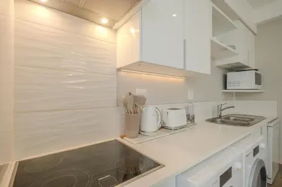 a white kitchen with a sink and a counter top at Luxury 2BR Loft with Patio Near Menlyn at the Regency in Pretoria