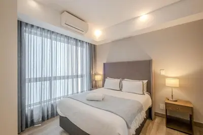 a bedroom with a large bed with a large window at Luxury 2BR Loft with Patio Near Menlyn at the Regency in Pretoria