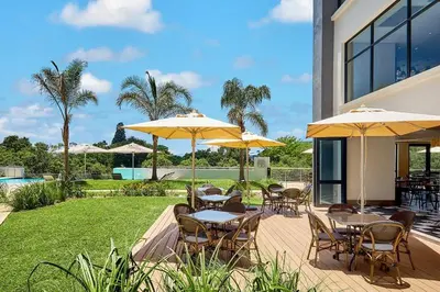 a patio with tables and chairs with umbrellas at Luxury 2BR Loft with Patio Near Menlyn at the Regency in Pretoria