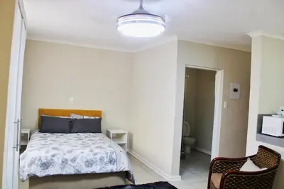 a bedroom with a bed and two chairs at Maruleng Guest House in Hoedspruit