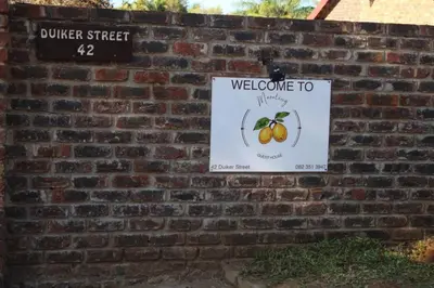 a sign on a brick wall with a welcome to sign at Maruleng Guest House in Hoedspruit