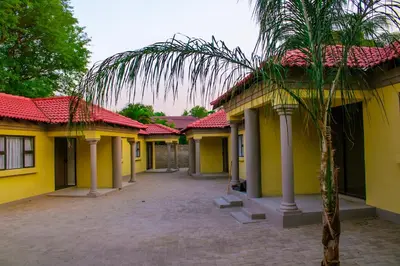 a row of yellow houses with a palm tree in front at Maruleng Guest House in Hoedspruit