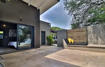 a patio of a house with a bench and a bed at Umkhaya in Marloth Park