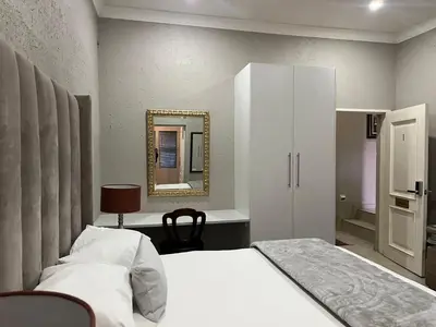 a bedroom with a white bed and a mirror at Fair Glen in Kyalami