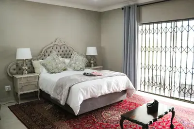 a bedroom with a bed and a large window at Fair Glen in Kyalami