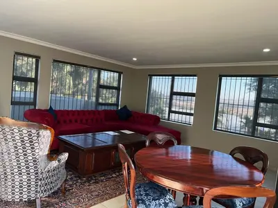 a living room with a red couch and a table at Fair Glen in Kyalami