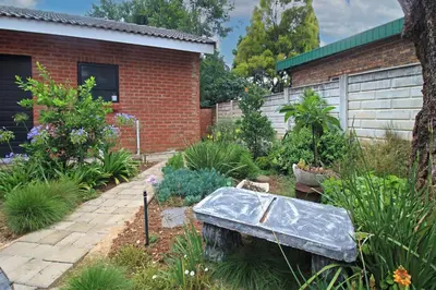 a garden with a stone bench in front of a house at The Chameleon Stay @107 in Centurion