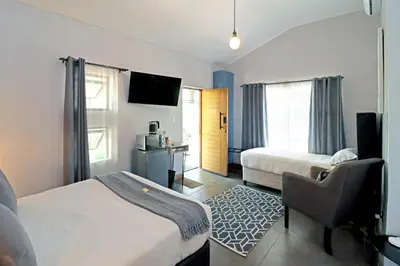 a hotel room with two beds and a chair at The Chameleon Stay @107 in Centurion