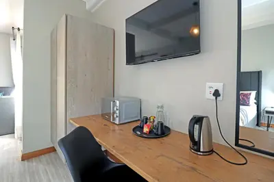 a wooden table with a tv on a wall at The Chameleon Stay @107 in Centurion