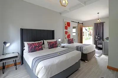 a hotel room with two beds and a desk and a room at The Chameleon Stay @107 in Centurion