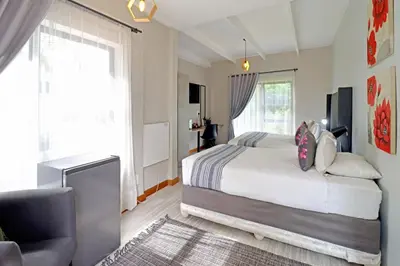 a bedroom with a bed and a chair and window at The Chameleon Stay @107 in Centurion