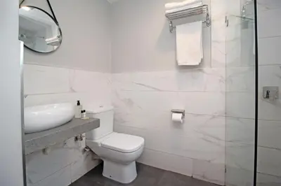 a white bathroom with a toilet and a sink at The Chameleon Stay @107 in Centurion