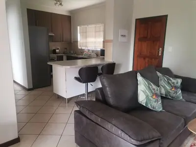 a living room with a couch and a kitchen at Centurion Cosy Apartment in Centurion