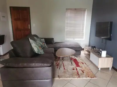 a living room with a leather couch and a table at Centurion Cosy Apartment in Centurion