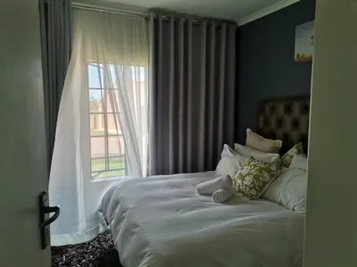 a bedroom with a large bed with a window at Centurion Cosy Apartment in Centurion
