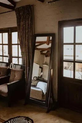 a mirror in a room with a bed and a window at African Leaves Trout Lodge in Dullstroom