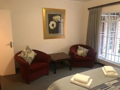 a bedroom with two chairs and a table and a bed at Hornbill Helipad 1 in Centurion