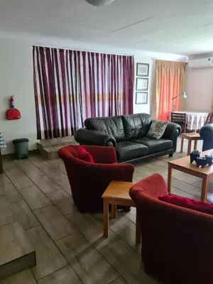 a living room with a black leather couch and chairs at Hornbill Helipad 1 in Centurion