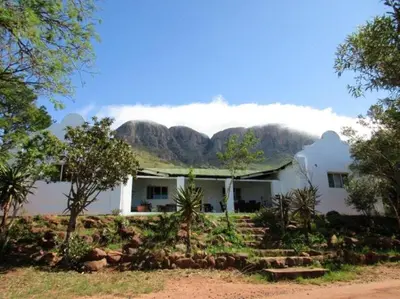 a white house with a mountain in the background at Griffons Nest in Thabazimbi