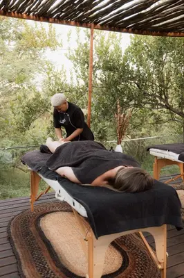 a woman laying on a bed on a blanket at Maroelani Lodge- Greater Kruger Private Reserve in Hoedspruit