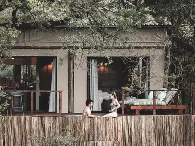 a man and a woman sitting on a fence at Maroelani Lodge- Greater Kruger Private Reserve in Hoedspruit
