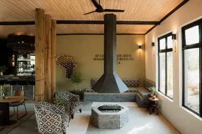 a living room with a fireplace and a table and chairs at Maroelani Lodge- Greater Kruger Private Reserve in Hoedspruit
