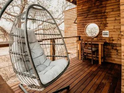 a swing sitting on a deck in a cabin at Maroelani Lodge- Greater Kruger Private Reserve in Hoedspruit