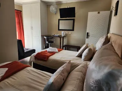 a hotel room with two beds and a couch at SOUTHY INN BY THE LAKE in Benoni