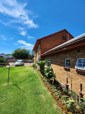 a house with a grass yard next to a building at SOUTHY INN BY THE LAKE in Benoni
