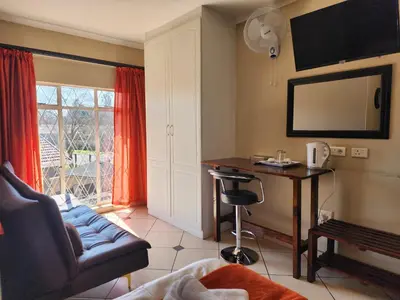 a living room with a couch and a desk and a television at SOUTHY INN BY THE LAKE in Benoni
