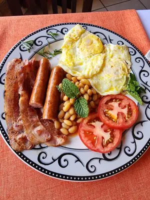 a plate of breakfast food with eggs bacon beans and tomatoes at SOUTHY INN BY THE LAKE in Benoni