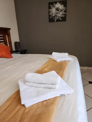 two white towels are sitting on top of a bed at SOUTHY INN BY THE LAKE in Benoni