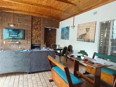 a living room with a table and chairs and a tv at Lesedi Guesthouse Middleburg in Middelburg