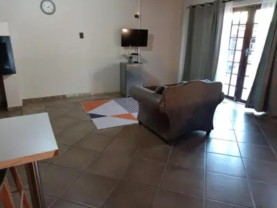a living room with a couch and a tv at Lesedi Guesthouse Middleburg in Middelburg