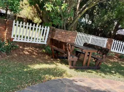 a wooden bench next to a white fence at Lesedi Guesthouse Middleburg in Middelburg