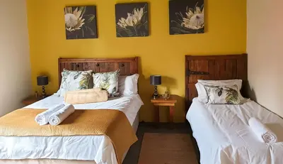 two beds in a room with yellow walls at The Outpost Dullstroom in Dullstroom