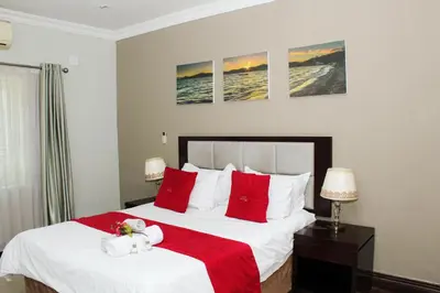 a bedroom with two beds with red and white pillows at The Pillows Suite in Pretoria